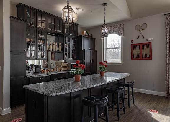Elegant clubhouse kitchen at Queens Gate Apartments, featuring granite countertops, bar seating, and stylish cabinetry, perfect for resident events and gatherings.