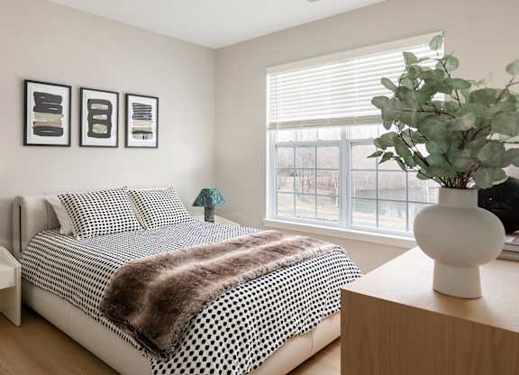 A bedroom with a bed, nightstands, and a plant.