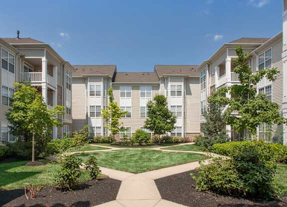an exterior view of an apartment building with a lawn and trees