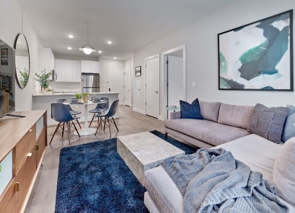 Modern open floor plan living room and kitchen in a luxury apartment rental at The Mint Rahway, featuring sleek furniture and decor.