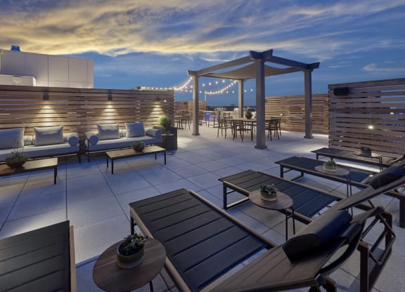 Luxurious rooftop lounge at night at The Mint Rahway, with comfortable seating, pergolas, and string lights, providing a serene atmosphere.