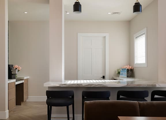 A kitchen with a white countertop and black chairs.
