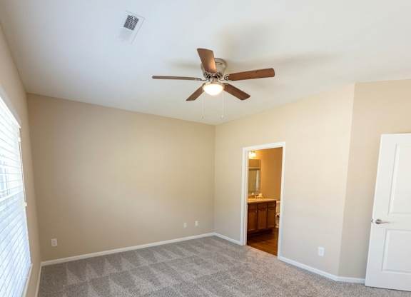 A room with a ceiling fan and carpeted floor.