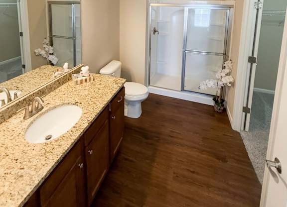 A bathroom with a sink, mirror, toilet, and shower.