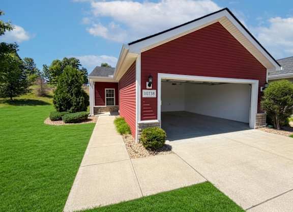 A red house with a white garage door and a black number plate.