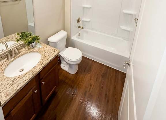 A white toilet is in a bathroom with a sink and a shower.