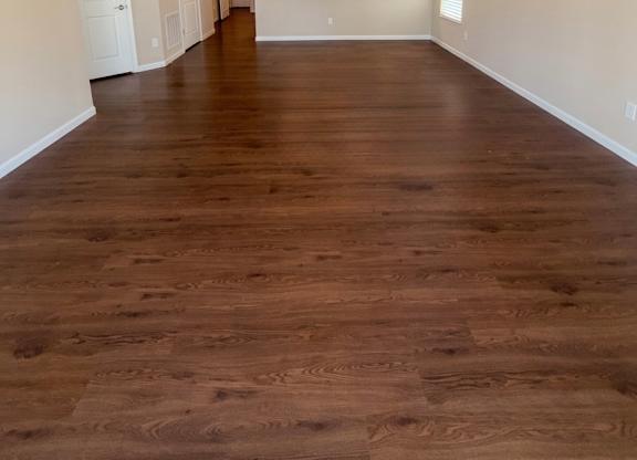 A room with a ceiling fan and wooden flooring.
