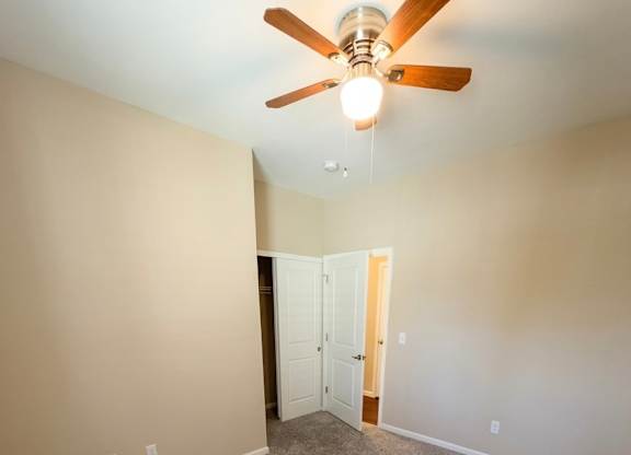 A room with a ceiling fan and carpeted floor.