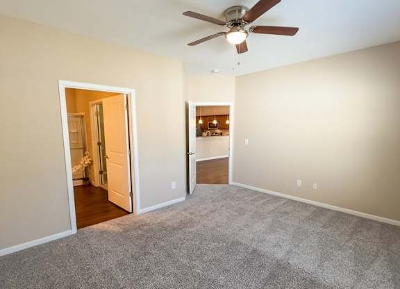 A room with a ceiling fan and carpeted floor.