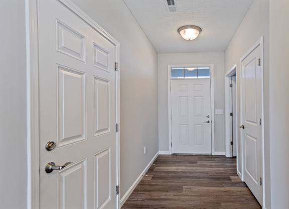 A long white hallway with a door at the end.