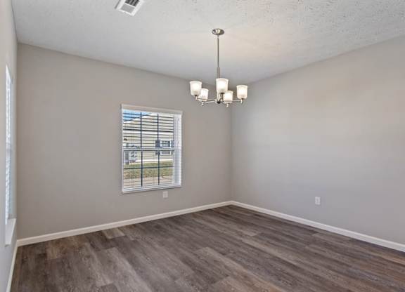 A room with wooden flooring and a window with blinds.