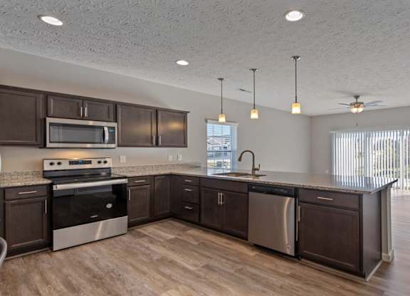 A kitchen with dark wood cabinets and stainless steel appliances for modern living at The Villages of Florence and Weaver Mill