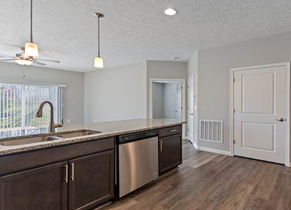 A kitchen with dark wood cabinets and a stainless steel dishwasher at The Villages of Florence and Weaver Mill