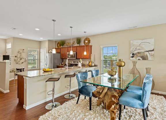 A modern kitchen with a glass table and blue chairs in a home for rent in a Florence, KY private community