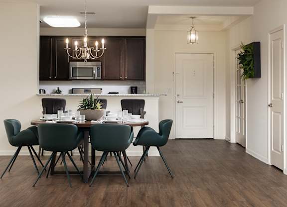 A modern dining room with a dark wood floor and white walls.