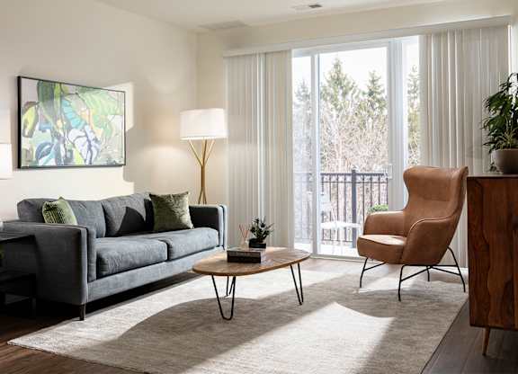 A living room with a grey couch, a wooden table, and a painting on the wall.