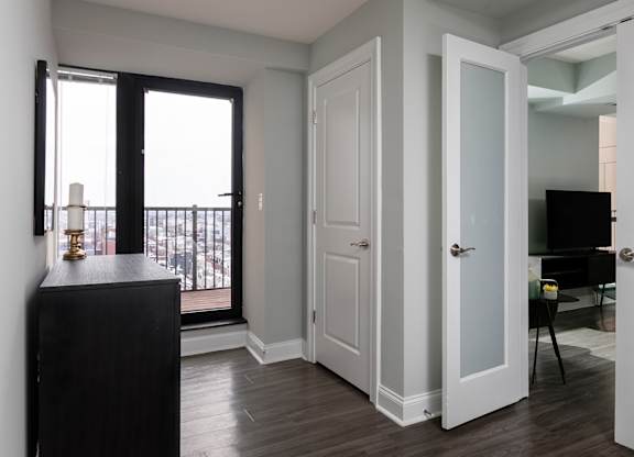 A black cabinet sits in a white room with a balcony.
