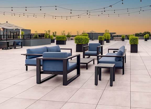 Spacious rooftop area with lounge furniture, string lights and skylines views at The Botanic apartments in Carteret, NJ
