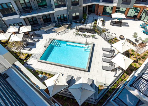Aerial view of the refreshing swimming pool at The Mint Rahway, surrounded by lounging areas and umbrellas, ideal for residents of this luxury apartment rental community.