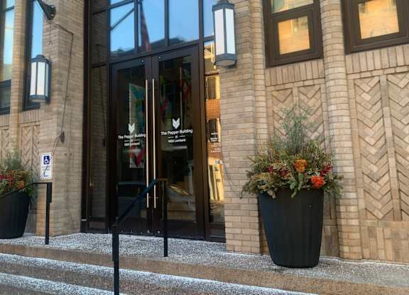 A building entrance with a glass door and a sign on the wall.