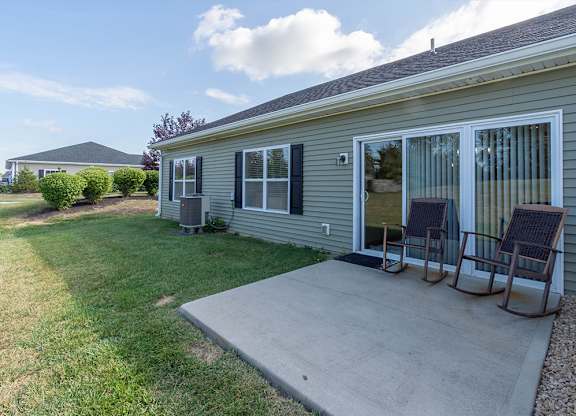 A house with a grey siding and a grey roof with a patio and two chairs.