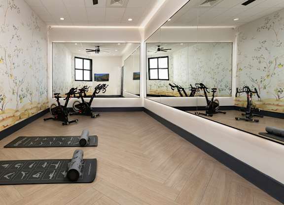 A room with exercise equipment and mirrors on the wall.