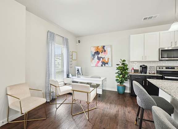 A white desk with a chair in front of a window with a painting on the wall.