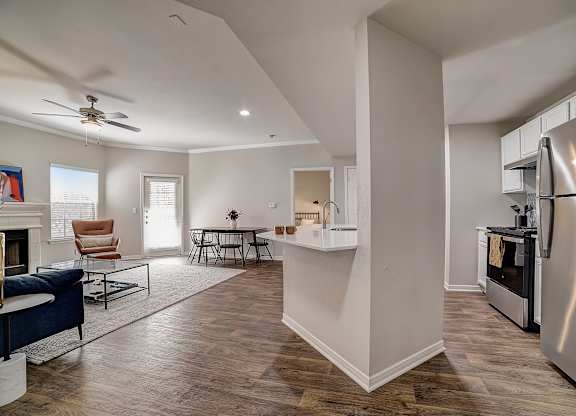 Open floor plan connecting kitchen and living room with breakfast bar and stainless range.