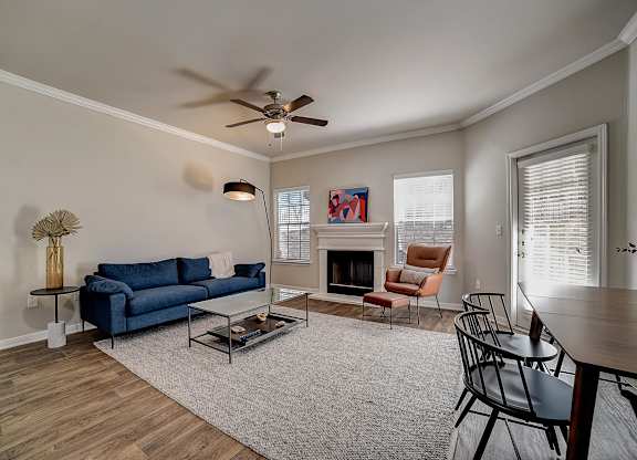 Living area with white mantel fireplace, big windows, and adjacent dining space.