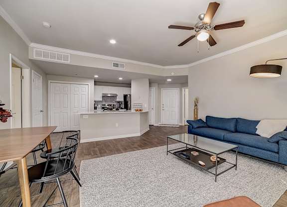 Spacious living room with ceiling fan, large rug, and pass-through kitchen bar.