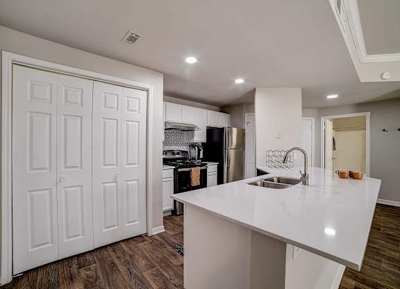 Kitchen island with sink and nearby double-door pantry storage.