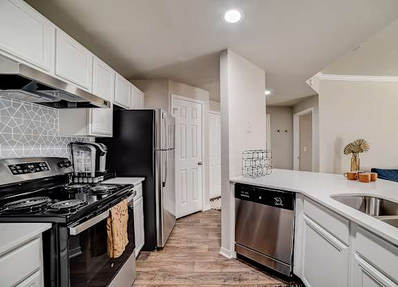 Kitchen workspace with stainless appliances, dishwasher, and double-basin sink on peninsula.