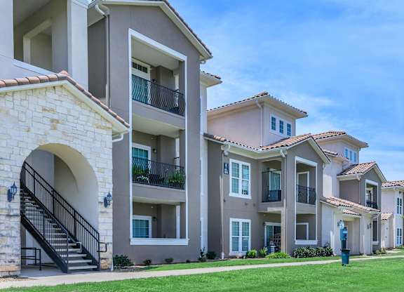 A row of apartment buildings with balconies and a clear blue sky.