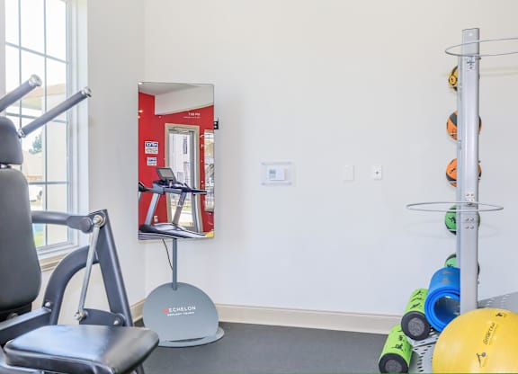 A gym room with a rowing machine and a ball.