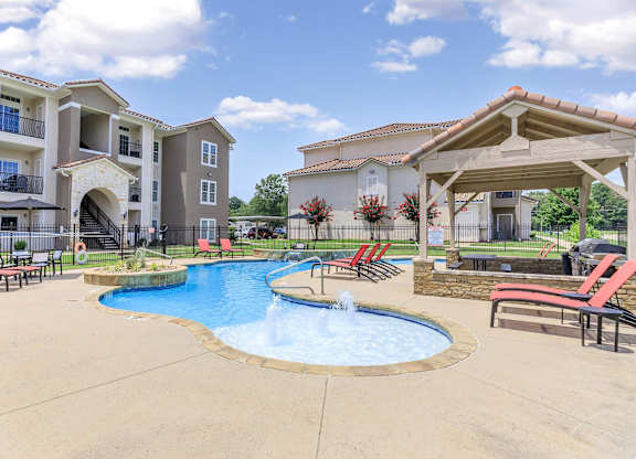 A large outdoor swimming pool with a fountain in the middle of it.