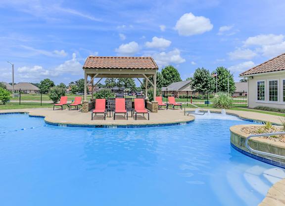A pool with a gazebo and chairs around it.