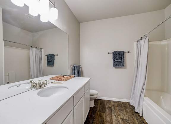 Bathroom with wide vanity, oversized mirror, and tub-shower combination.