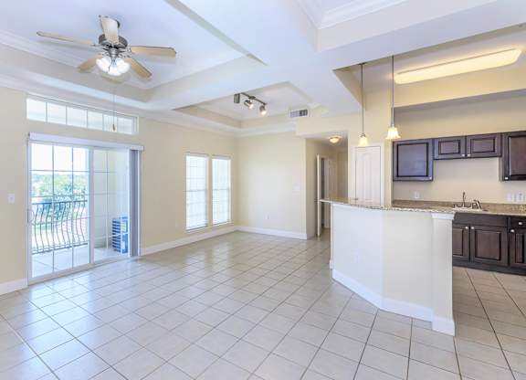 A spacious kitchen and living room with a ceiling fan and sliding glass doors.