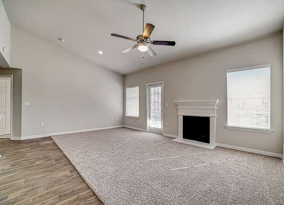 Living room featuring mantel fireplace, ceiling fan, and plenty of natural light.