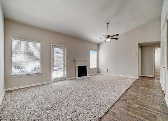 Large carpeted living room with ceiling fan, fireplace, and patio-style door.