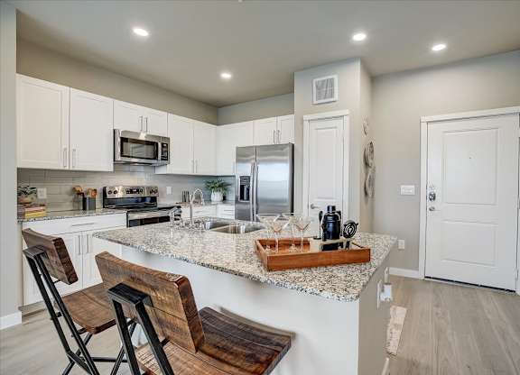 Bright kitchen with quartz island seating, double sink, and stainless appliances at Skyview North.