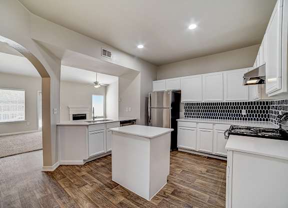 Bright kitchen with island, stainless refrigerator, and bold blue tile backsplash.