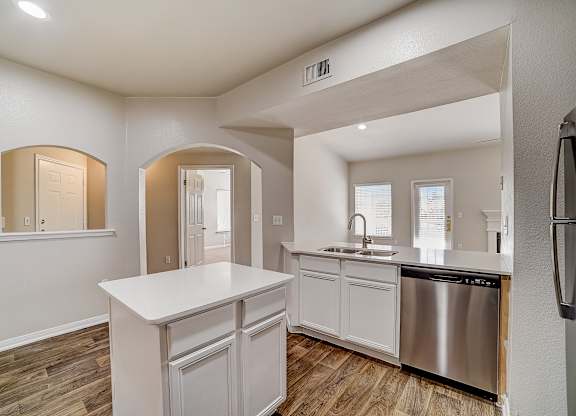 Kitchen with center island, double sink, and arched pass-through to entry hall.