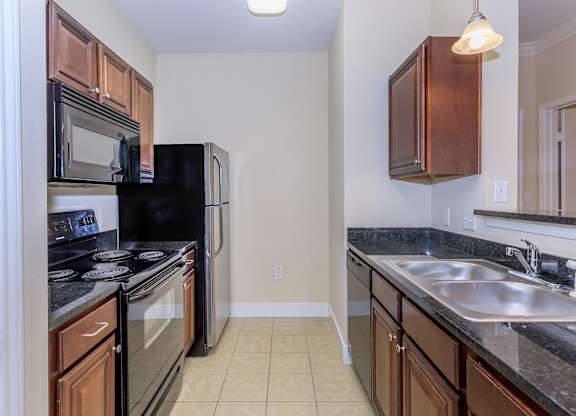 A kitchen with black appliances and brown cabinets.