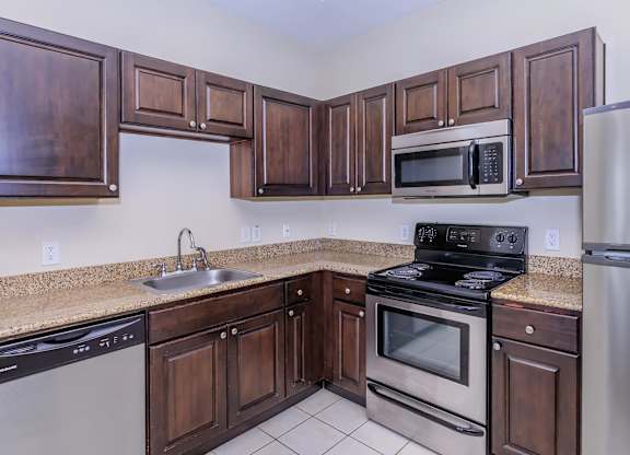 A kitchen with dark wood cabinets and stainless steel appliances.