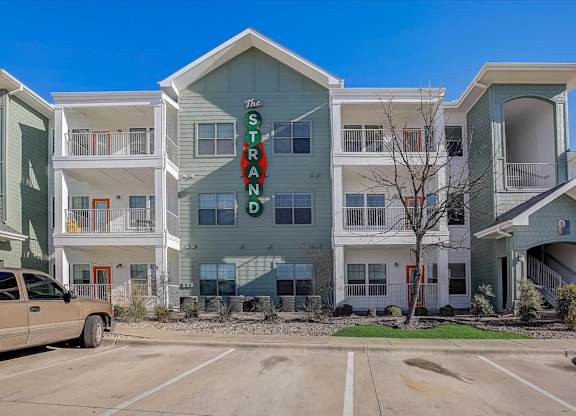 Three-story apartment building with balconies and green-and-white siding.
