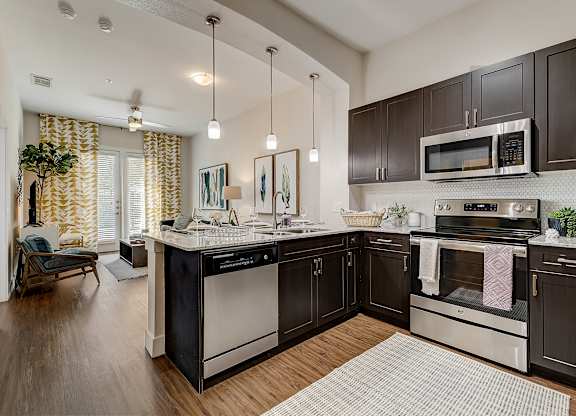 A modern kitchen with dark wood cabinets and stainless steel appliances.