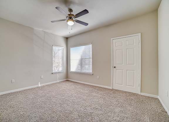 Carpeted bedroom with ceiling fan and corner windows for extra sunlight.