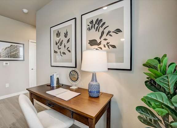 Dedicated desk nook with lamp lighting, framed artwork, and a comfortable upholstered chair.
