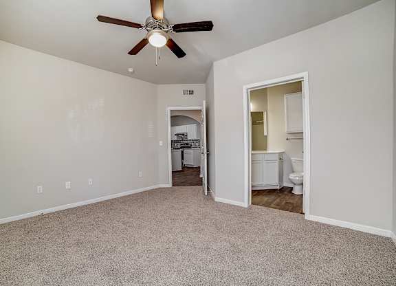 Bedroom view showing ensuite bathroom doorway and hall leading toward kitchen.